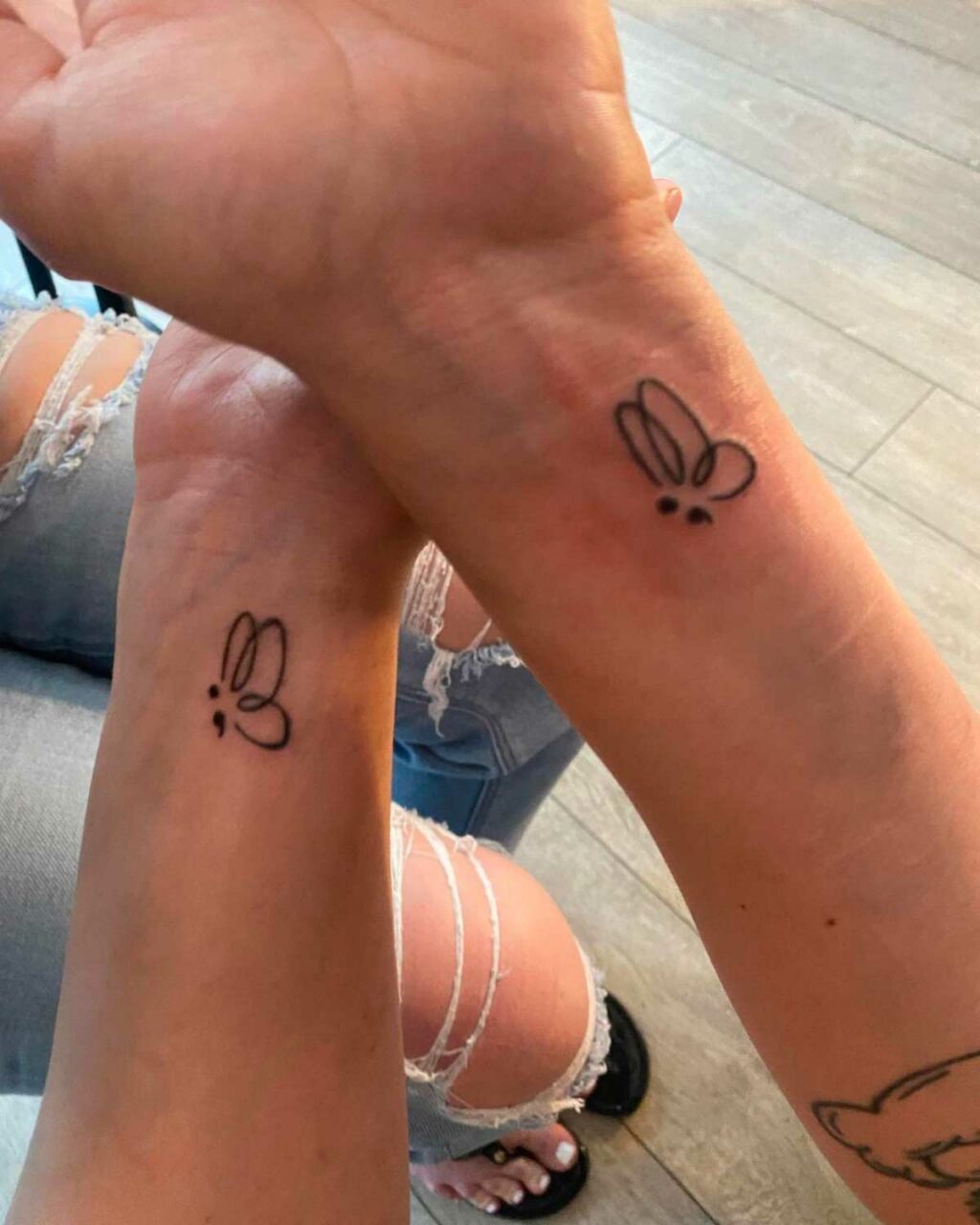 Two people with matching butterfly tattoos on their wrists, a symbol of their friendship and bond.