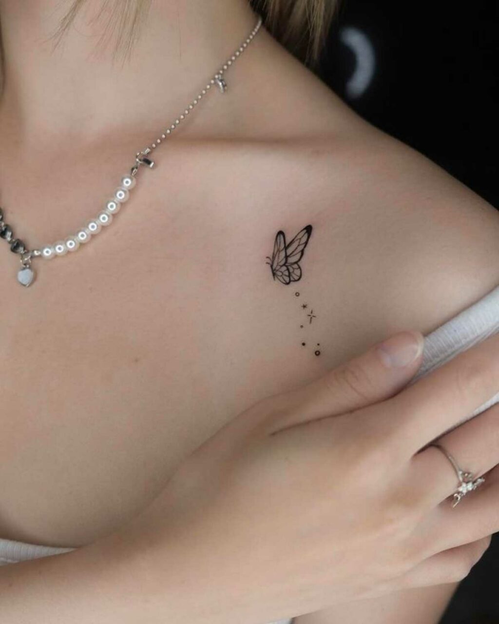 Small, black and white butterfly tattoo on a woman's shoulder, a delicate and meaningful design.